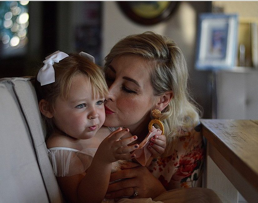Mom kissing toddler girl on the cheek